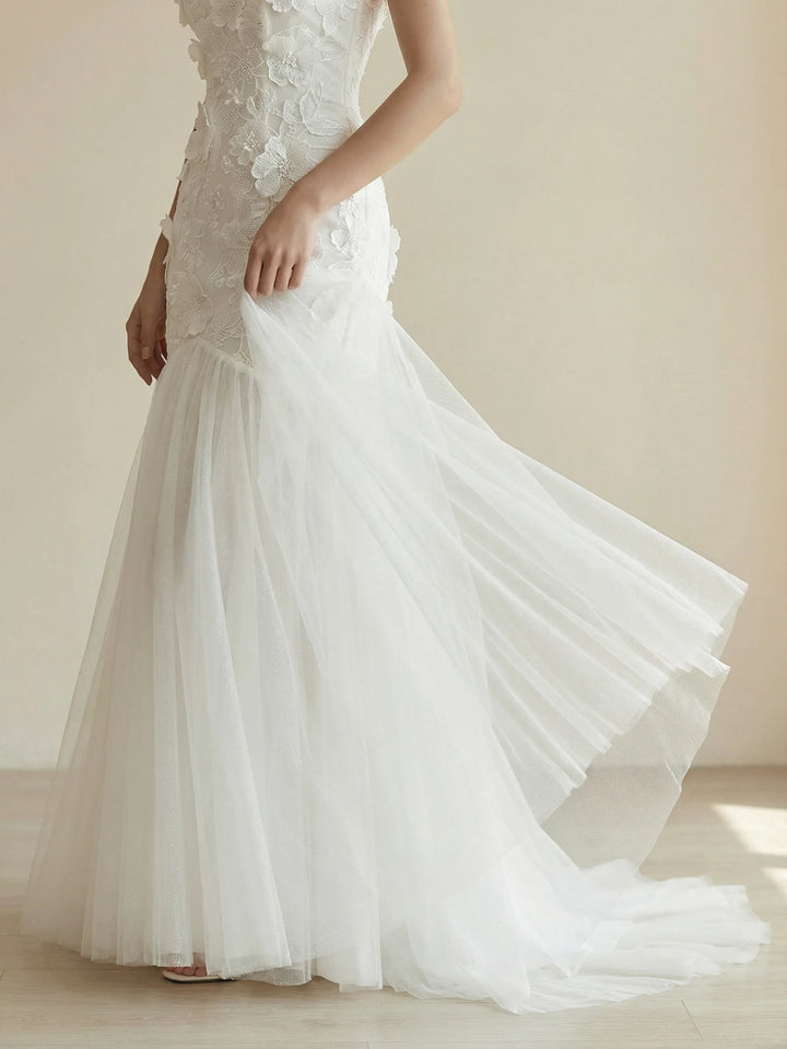 White appliqué bridal gown with fitted bodice and flowing tulle skirt with train