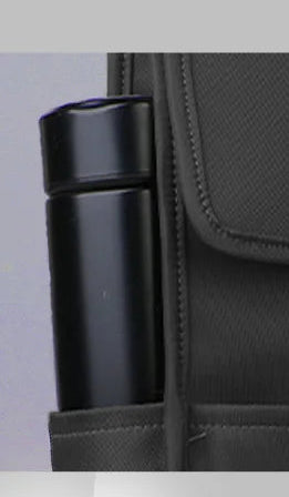 Black minimalist backpack with front flap, brown strap, and dual side pockets