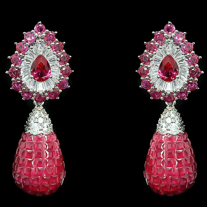 Pair of earrings with pink gemstones and red teardrop stones on a black background