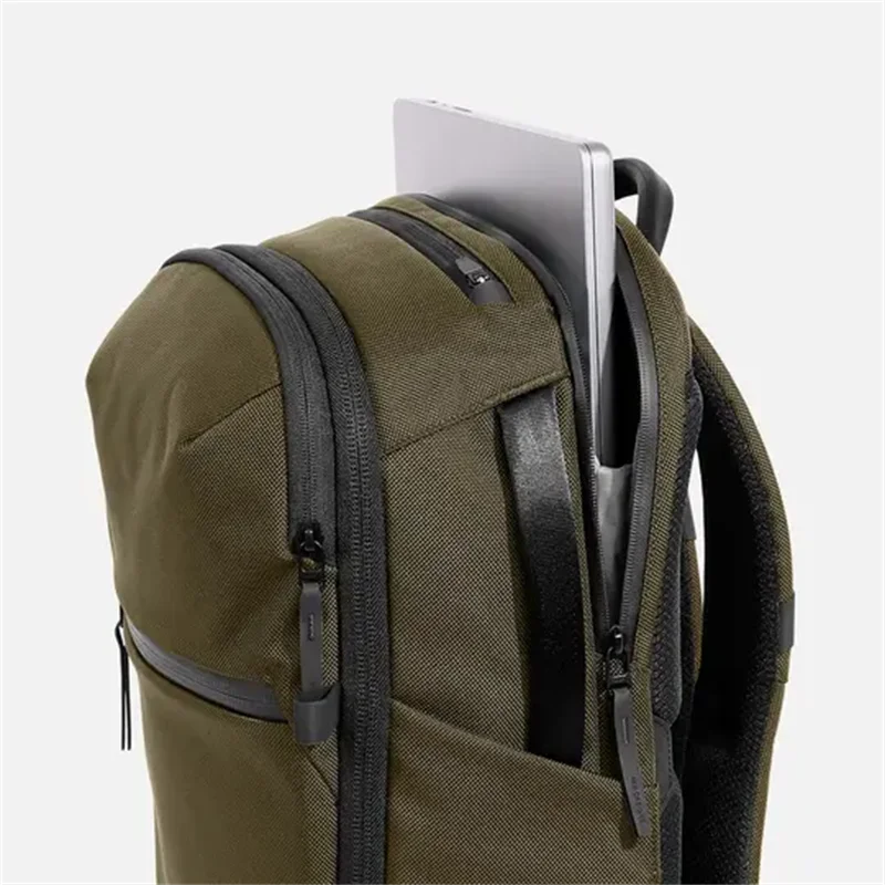 Olive green nylon backpack side panel with front zip pocket and streamlined profile