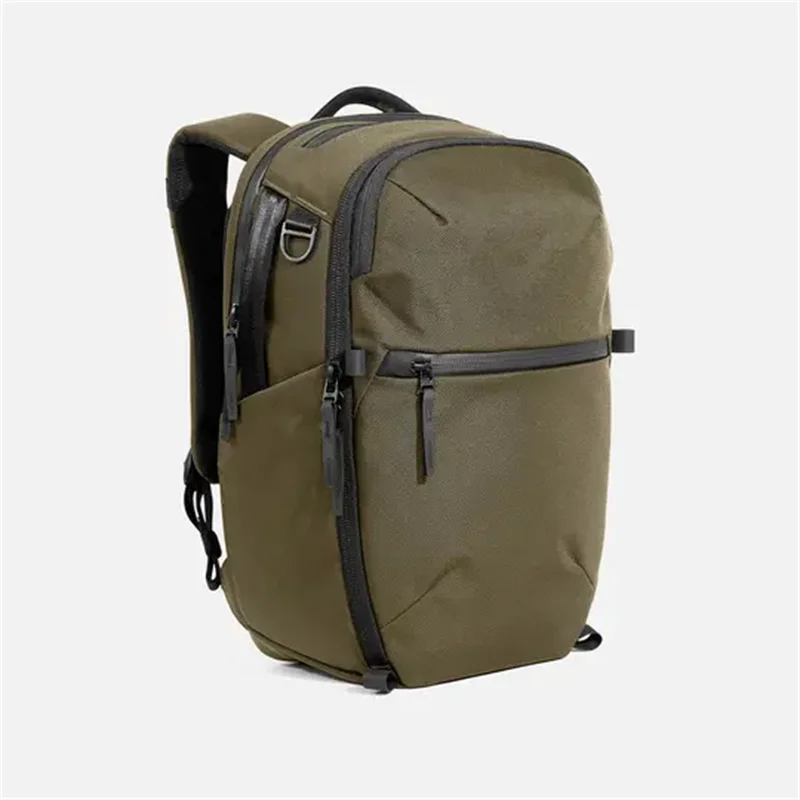 Olive green nylon travel backpack with front zip, top handle, and side straps