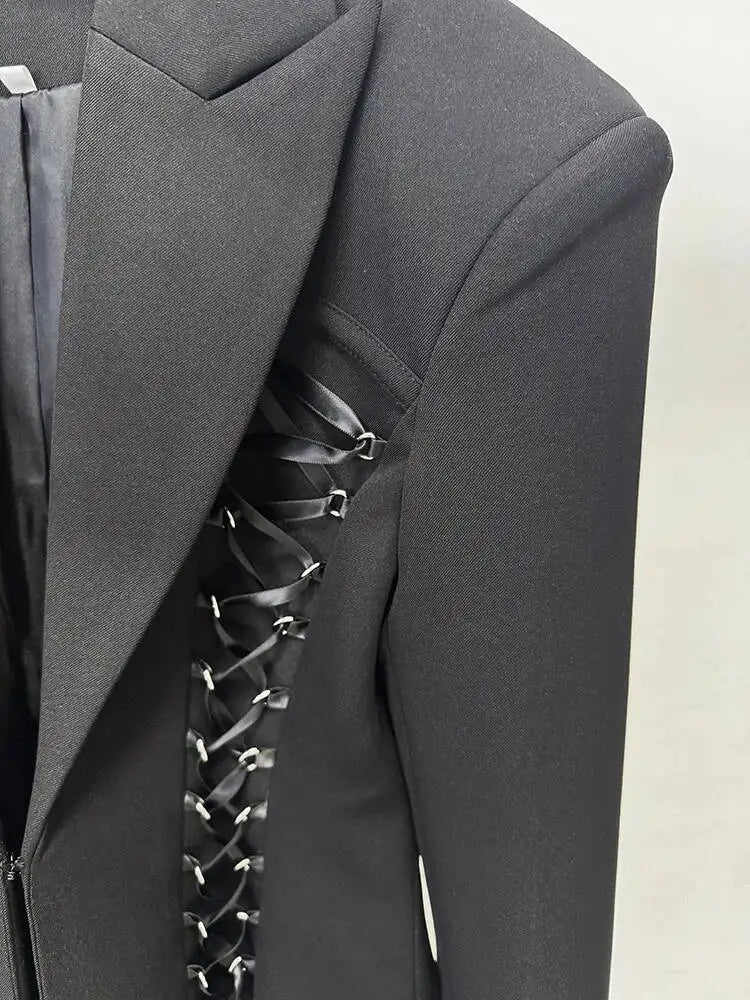 Close-up of black blazer lapel with decorative lace-up trim and metal eyelet details