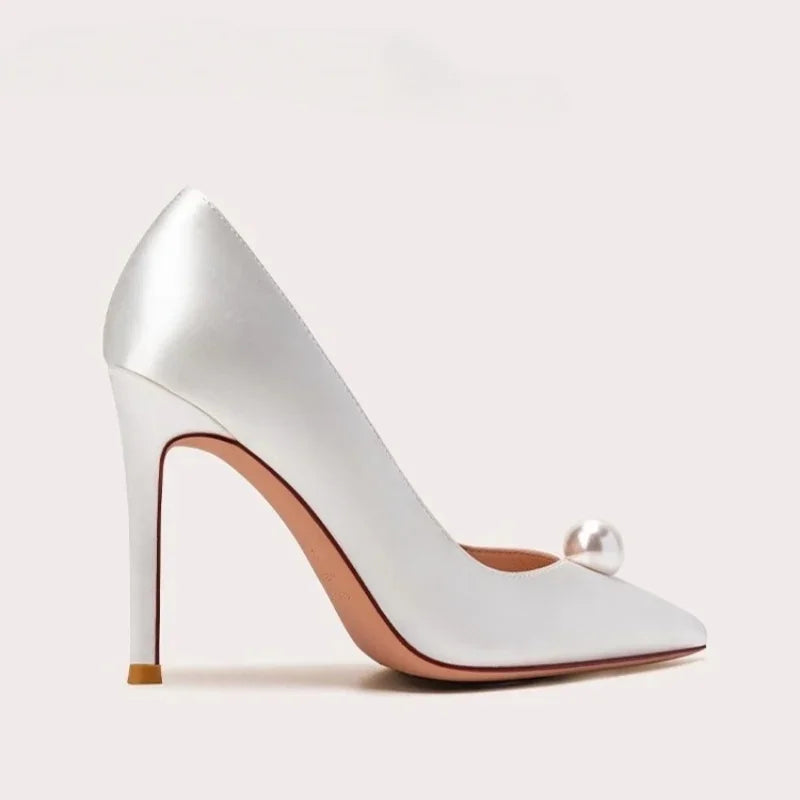 White satin slip-on pumps with pearl ornament, pointed toe, and gold stiletto heel