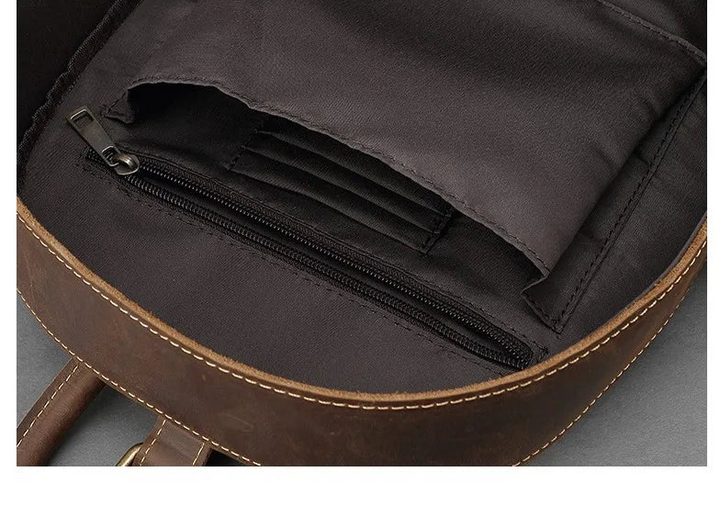 Interior zip pocket with stitched edges inside dark brown leather backpack.
