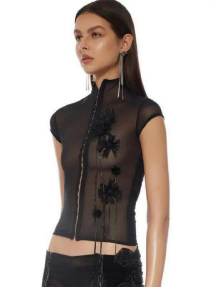 Black sheer top with floral embellishments on a white background