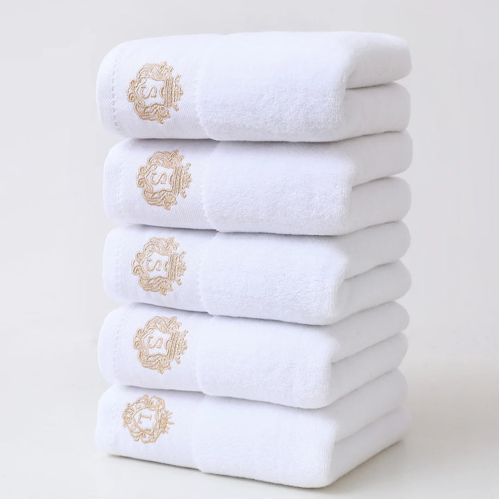White 5-piece bathroom towel set with gold embroidered monograms, folded stack