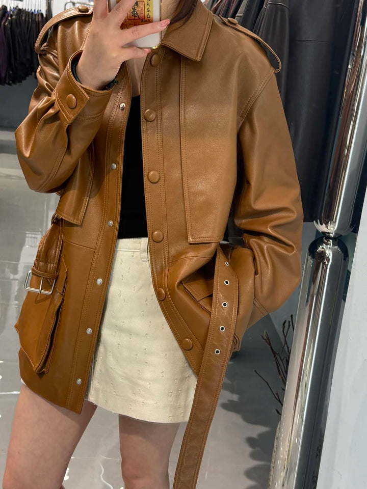 Belted tan-brown leather coat with flap pockets, snap buttons, and shoulder epaulets