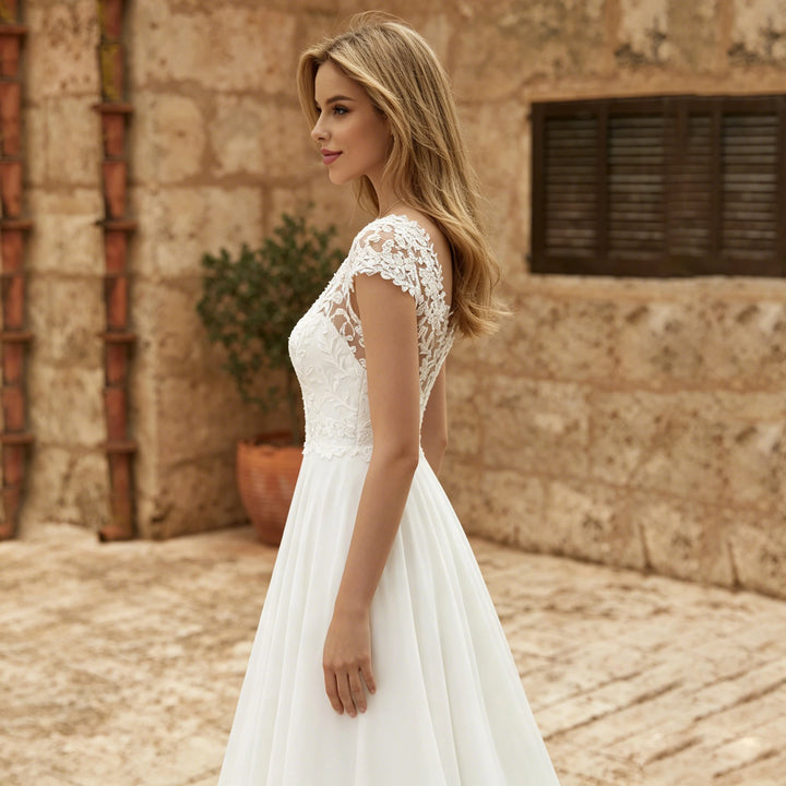 Ivory lace cap-sleeve bridal gown with fitted waist and pleated chiffon skirt, side view